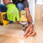 person using dewalt cordless impact driver on brown board